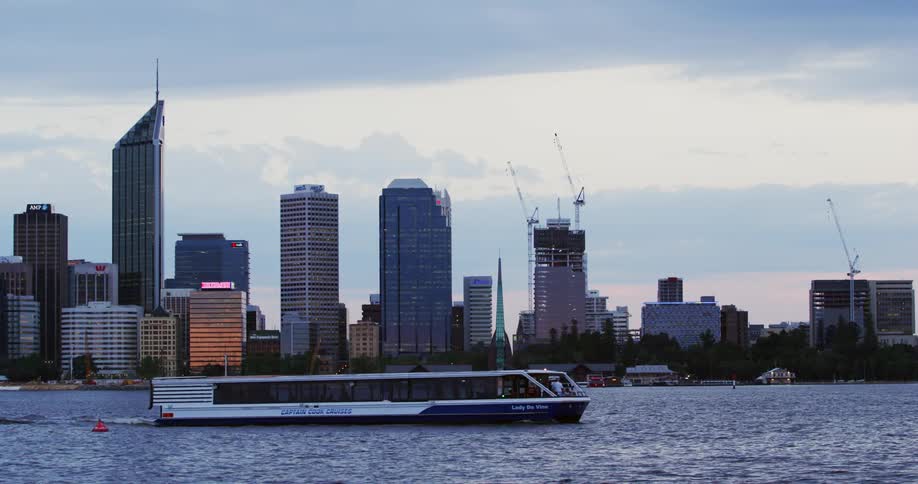 A boat passes on a river in front of a city skyline