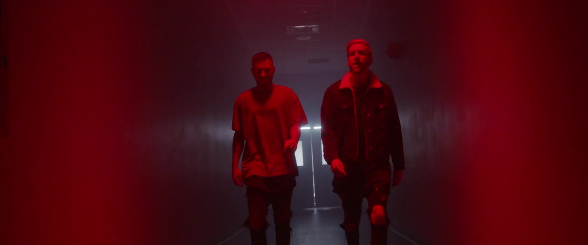 Two men walk down a hallway