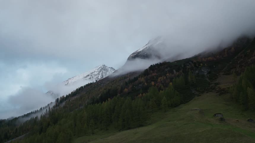 Clouds float around a tree-covered mountainside