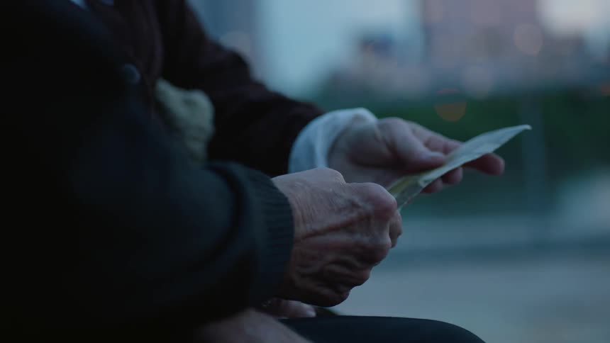 Two elderly people pass a pamphlet between one another