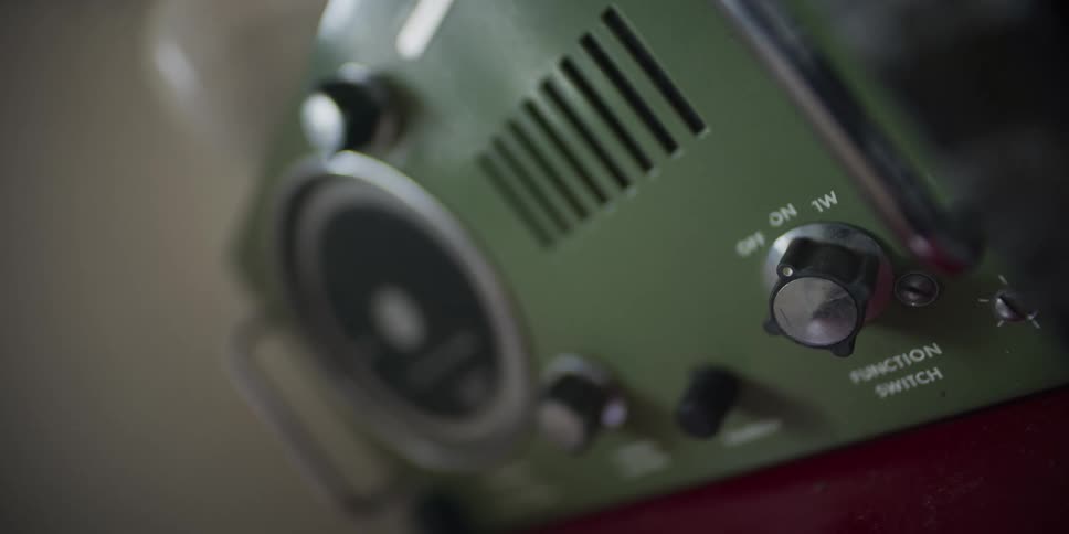 A slow focus pull reveals the function switch on a vintage green radio or electronic device