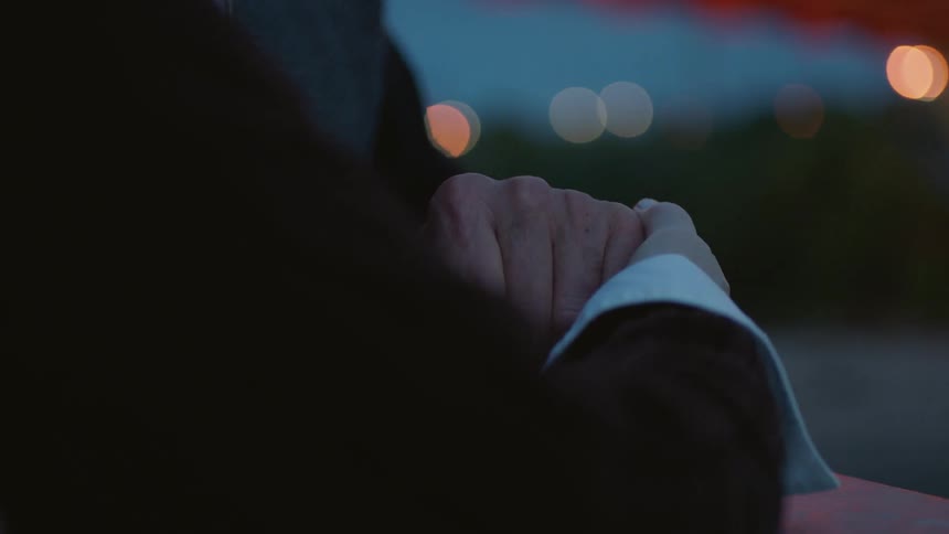 Person clasps hands outside at night