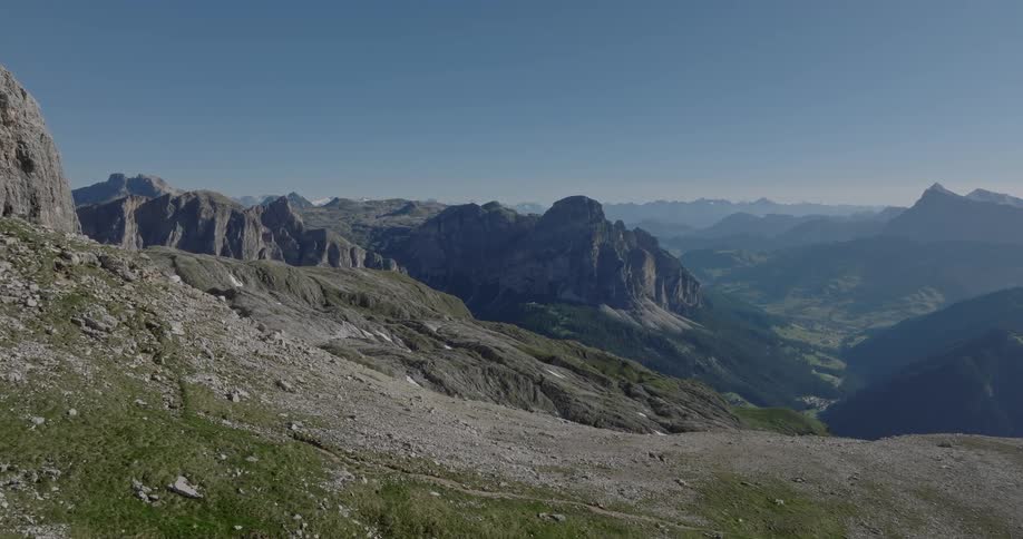 Epic and serene wide shot of a vast mountain range with a deep green valley below under a clear blue sky