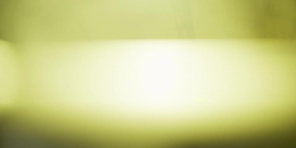 Atmospheric yellow fog drifts and glows under a bright industrial light