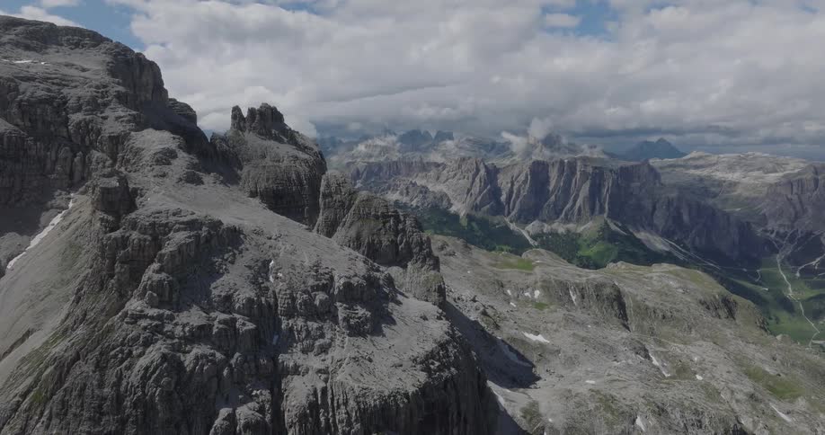 A slow aerial view pushes over the rocky, dramatic mountain peaks of a vast mountain range