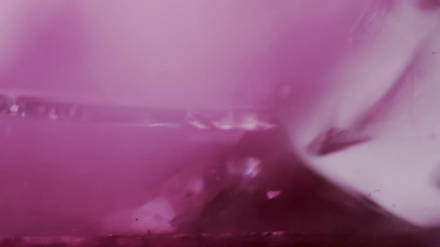 A glass shatters sending up a plume of purple dust