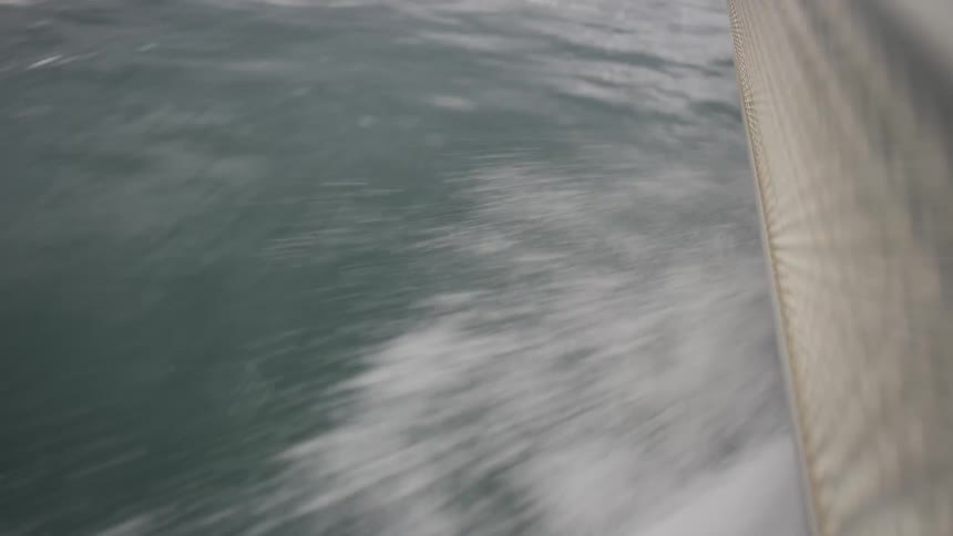 A close-up point-of-view shot from a speeding boat captures the churning water and wake alongside the hull