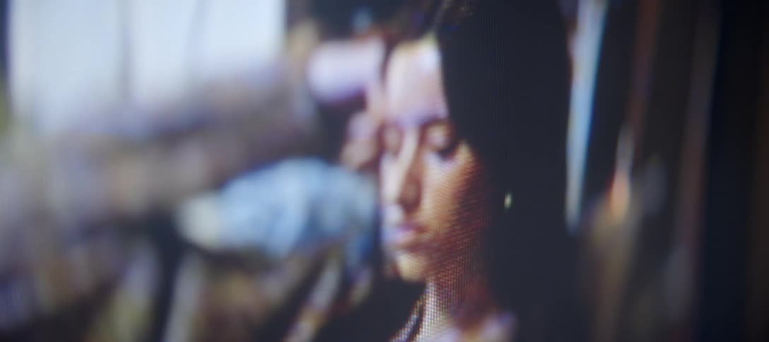 An abstract, macro shot captures the pixelated face of a woman on a digital display