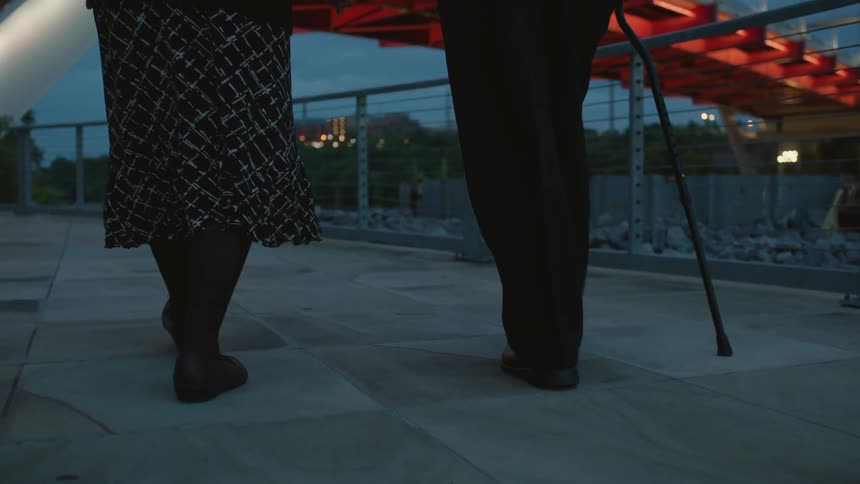 Two people walk along the pier towards a bridge at dawn