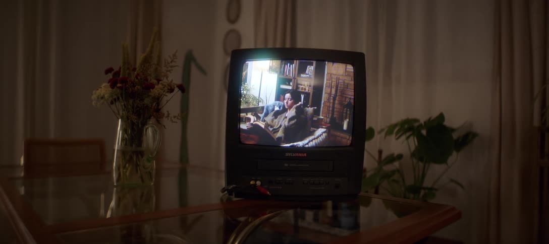 A slow push-in on a vintage television and VCR combo playing a movie in a dark room