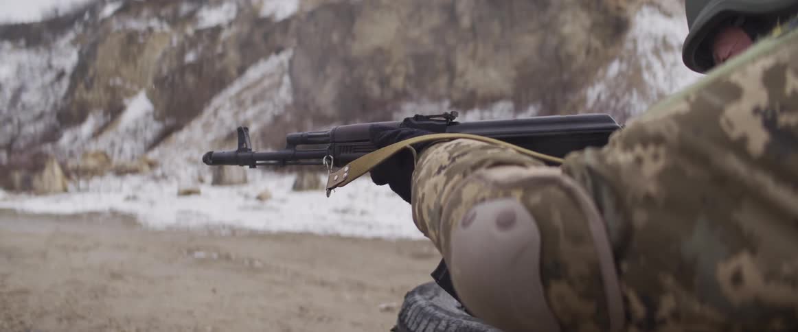 Close-up slow-motion view of an assault rifle being fired by a soldier in a snowy environment