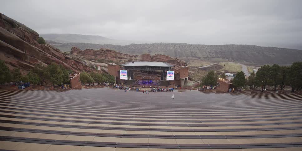 A band plays for a small crowd at the Red Rocks Amphitheater in Colorado on an overcast, rainy day