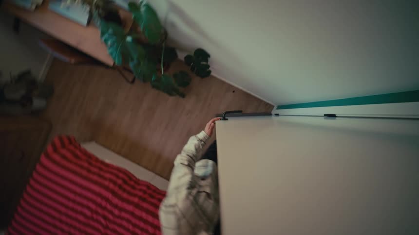 Creative high-angle shot of a man walking into a bedroom and opening a white sliding wardrobe