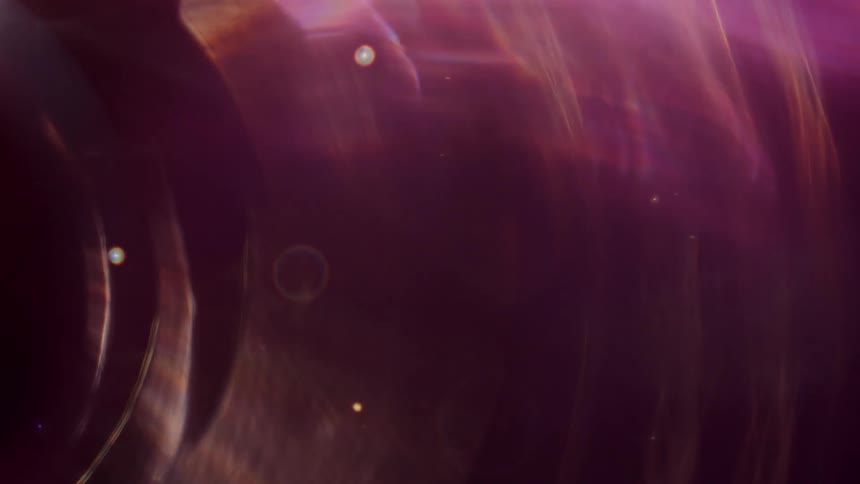 Ethereal purple and gold light leaks create a cosmic and dreamy abstract background with shifting bokeh orbs