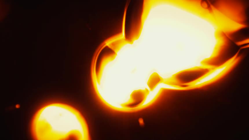 A mesmerizing close-up of abstract golden lava-like orbs morphing and glowing in the dark