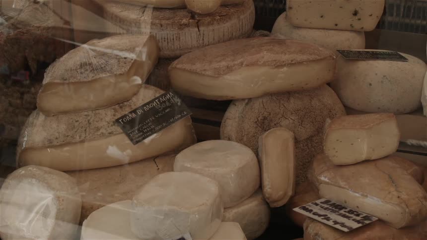 Wheels of cheese are stacked in a shop window