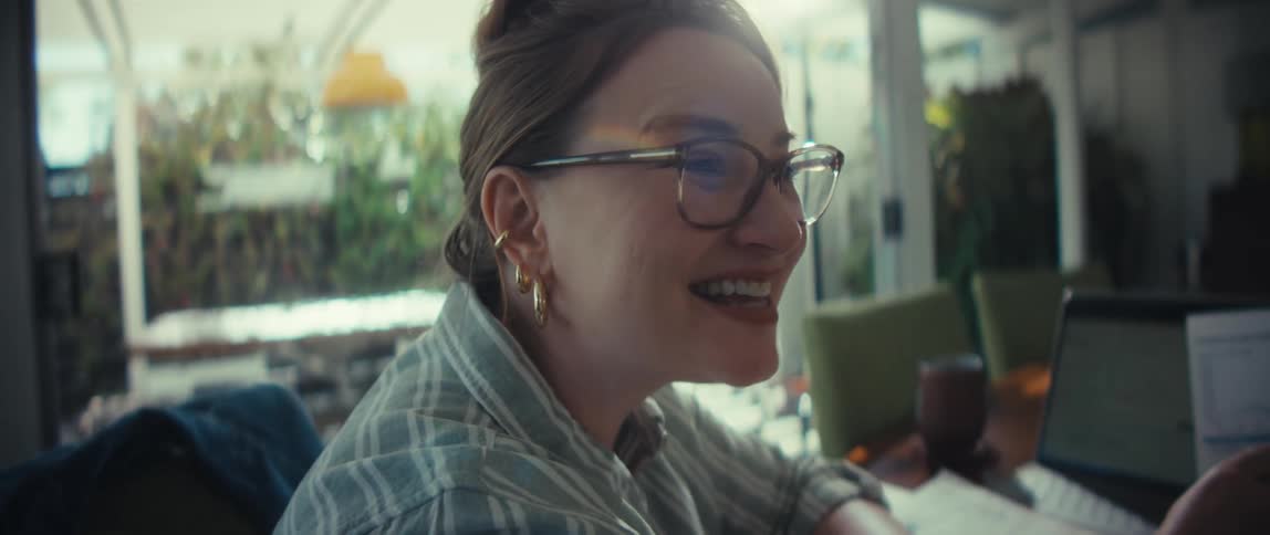 A financial advisor joyfully explains a successful investment portfolio's growth to her client using charts and a laptop