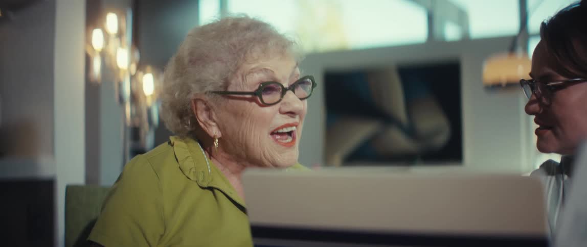 A financial advisor explains paperwork to a smiling senior woman in a modern home office