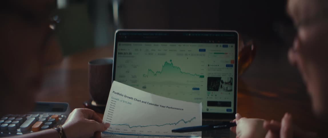A younger woman explains portfolio growth and performance to an older woman using charts on a laptop and paper