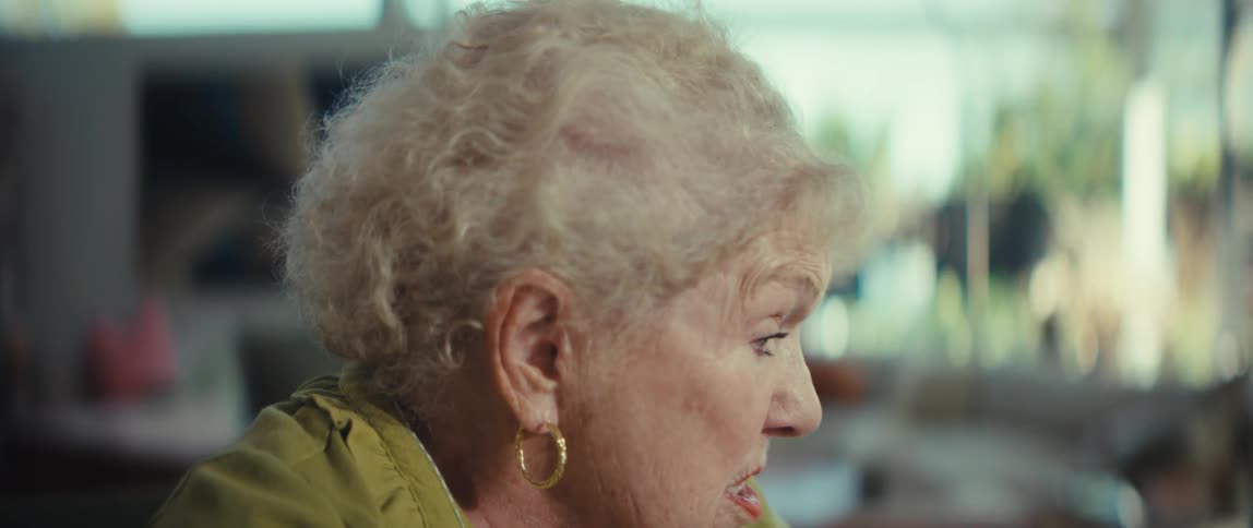 Close-up of an elderly woman wearing a hearing aid while engaged in a thoughtful conversation in her living room