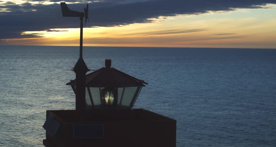 Time-lapse of a stunning sunrise over the ocean, with the silhouette of a modern lighthouse in the foreground