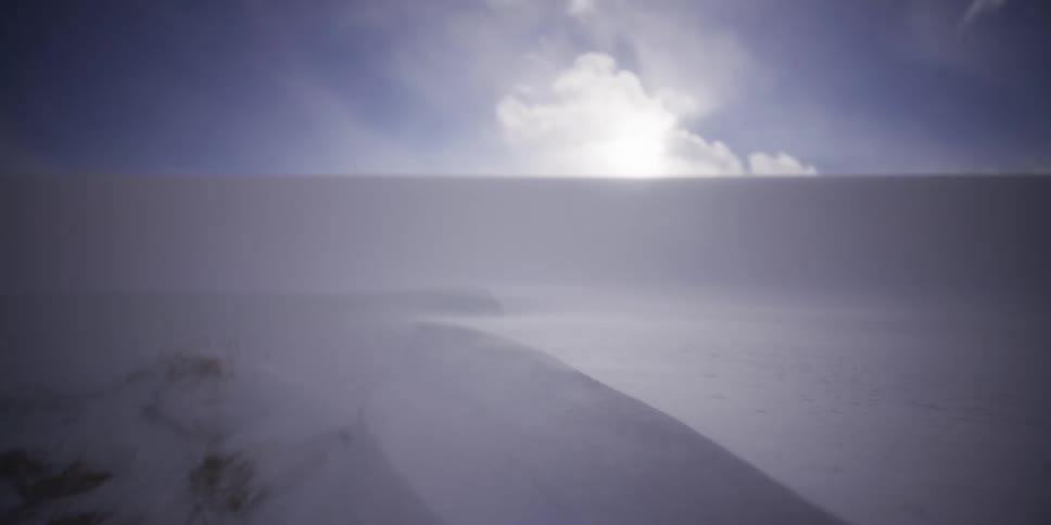 Blowing snow creates whiteout conditions next to a building during an intense winter storm