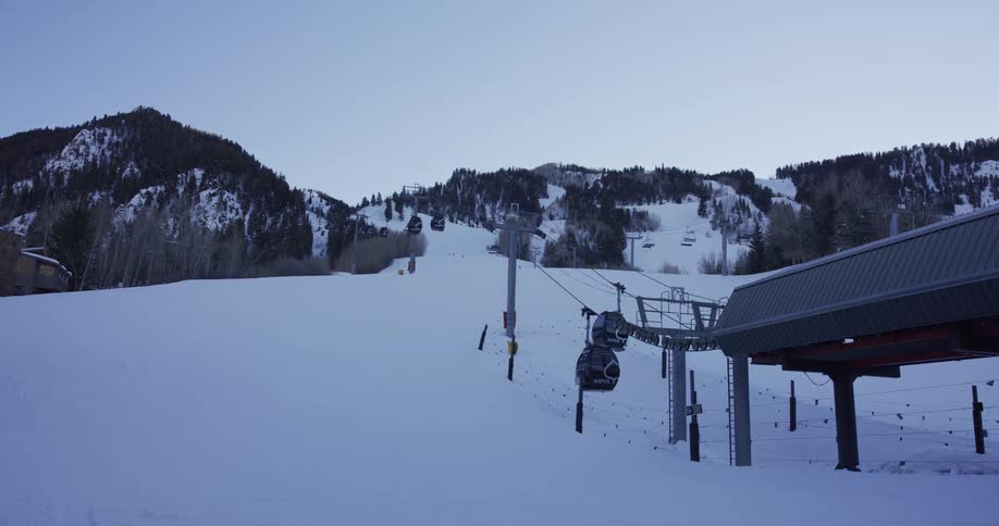 A serene view of gondolas ascending a snow-covered mountain at a ski resort during twilight