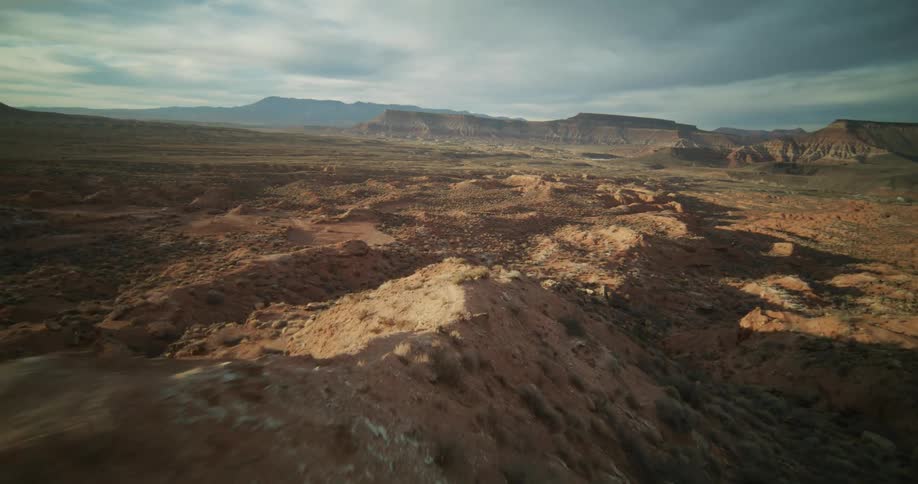 An exhilarating first-person view drone flight speeds along a rugged desert ridge above a vast red rock canyon