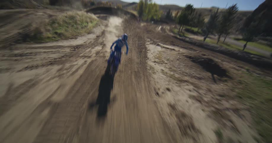 High-speed FPV drone chases a motocross rider racing down a winding dirt track