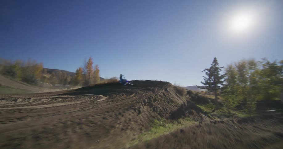 Dynamic slow motion follow shot of a motocross racer skillfully navigating a dirt curve, spraying dirt into the sunlight