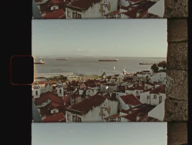 Vintage 8mm film captures a scenic view of Lisbon, Portugal's red rooftops overlooking the Tagus River harbor