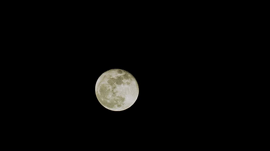 A static close-up shot of the full moon shining brightly against the dark night sky