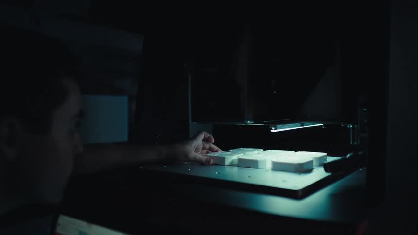 A technician carefully places white sample blocks into a high-tech machine and closes the lid to begin processing