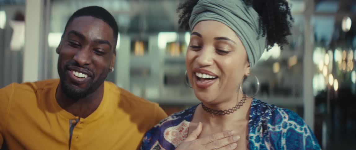 A happy African American man and woman share a joyful moment, laughing together in slow motion