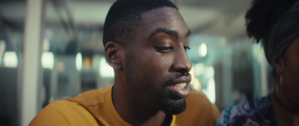 A close-up slow-motion shot of a young African American couple working and talking together on a laptop in a modern café
