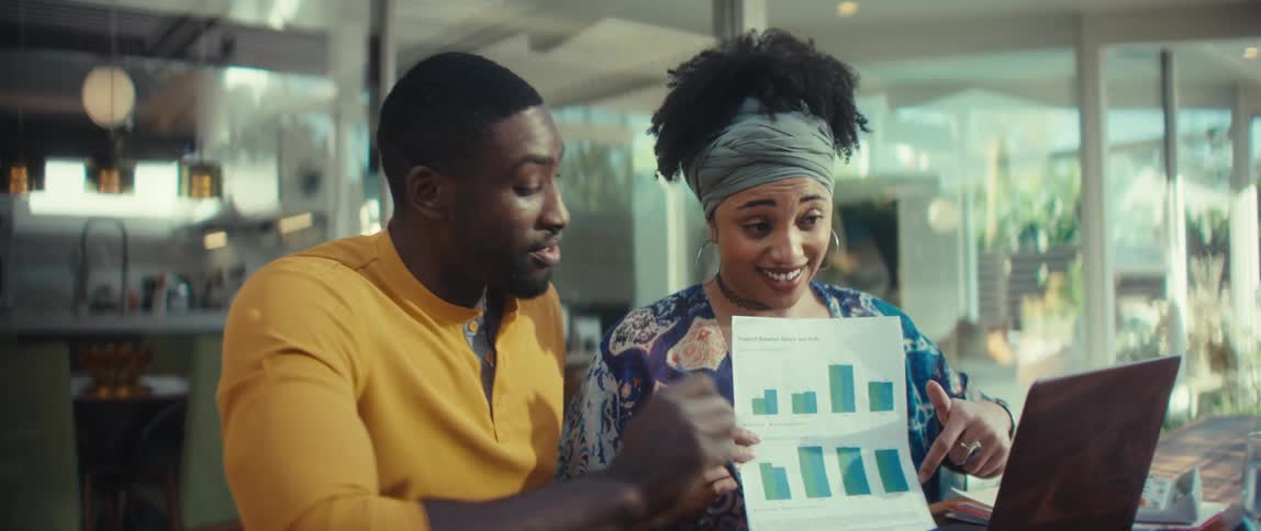 A young couple is thrilled with the positive results on a bar graph they are discussing during a video call on their laptop