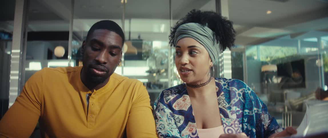 A creative man and woman collaborate on a project, sharing ideas while working on a laptop in a bright, modern office space