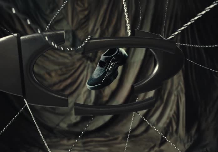 A sleek black shoe is suspended by chains as metallic logo pieces assemble around it in a dramatic reveal