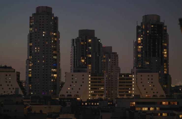 A wide shot of modern apartment buildings in Paris with their lights on against the dusky night sky