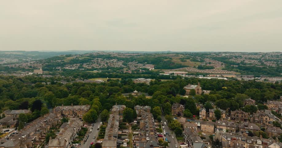 Aerial view flying over a historic English town with traditional stone houses and a large green park