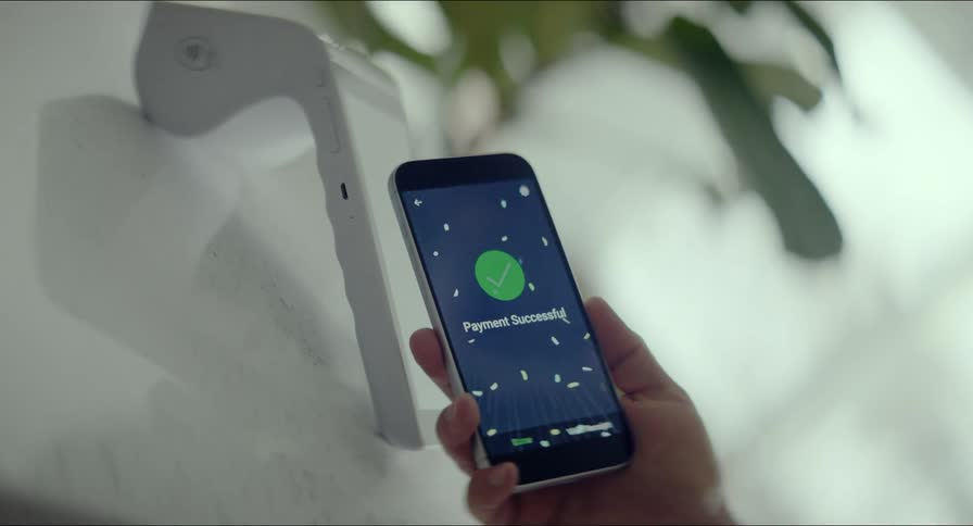 A dynamic, swirling shot captures a successful contactless payment made with a smartphone, confirmed by a celebratory animation on the screen