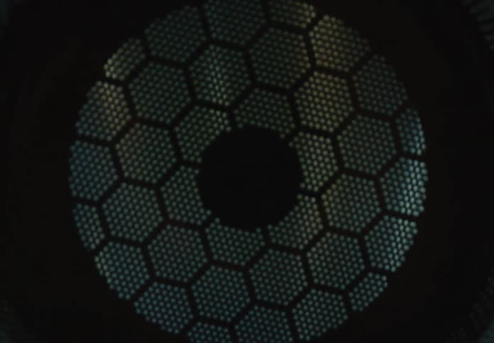 Close up abstract view of a futuristic metallic honeycomb grate with light reflecting off its surface