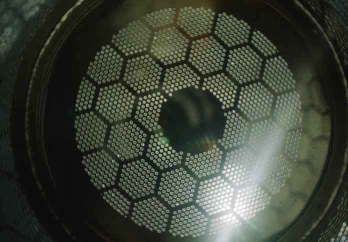 An abstract close-up of a moving light source flashing behind a futuristic metal honeycomb grid