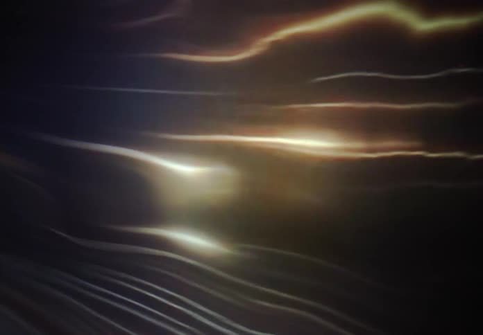Golden and white light streaks morph and flow in a mesmerizing abstract animation against a dark background