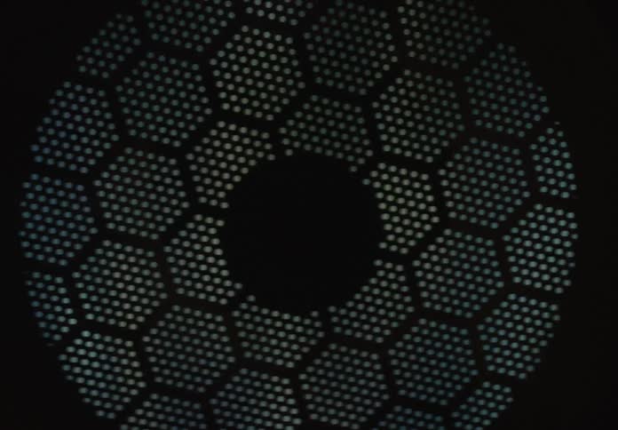A macro shot reveals a mesmerizing pattern on a perforated metal plate as light plays across its surface