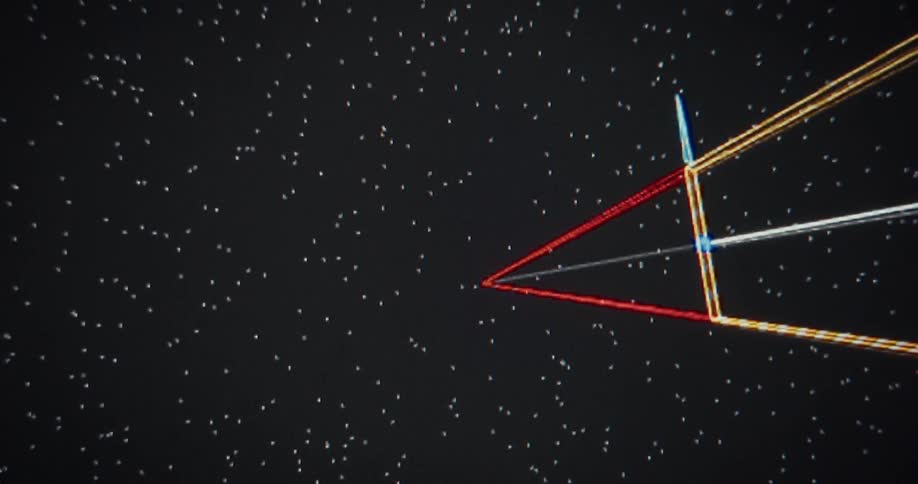 A colorful, abstract wireframe object slowly rotates and approaches through a field of stars in a vintage computer animation