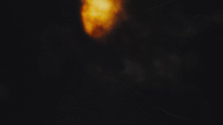 A fiery explosion burns amidst dark, roiling smoke against a black background with vintage film scratches