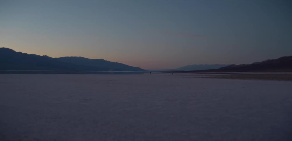 A serene twilight descends over the vast and quiet expanse of the Badwater Basin salt flats in Death Valley National Park