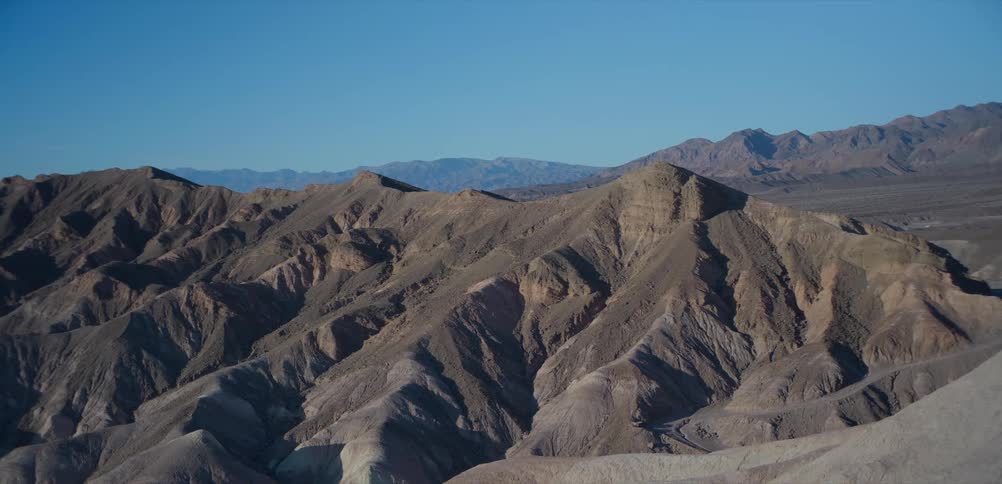 A beautiful wide view of the rugged desert mountains and canyons in Death Valley National Park under a clear blue sky