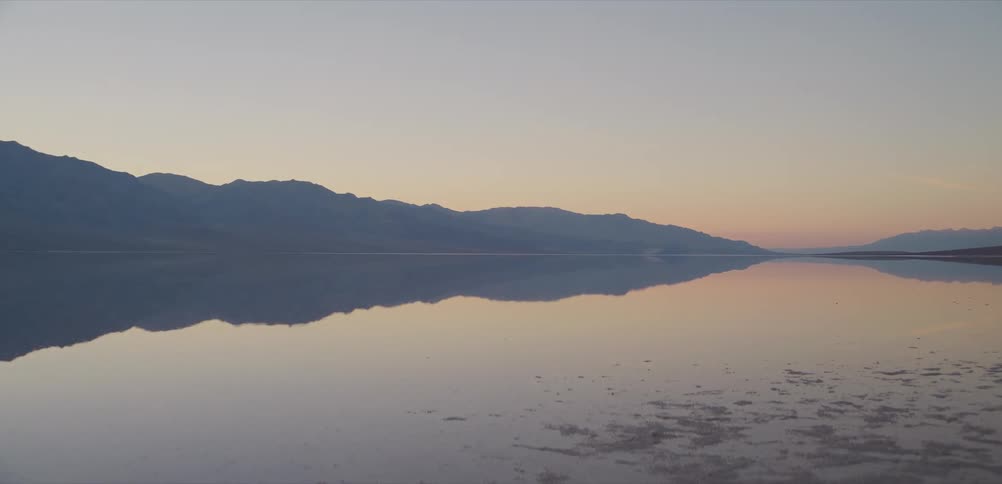 A stunning, symmetrical reflection of a mountain range on a still lake at sunrise